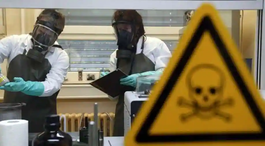 Two workers wearing bio-security gear and taking notes behind a warning sign. File photo.