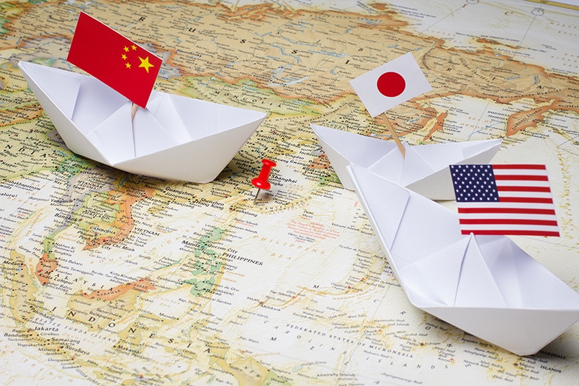 Map of Asia with three paper boats holding a China, a Japan and a US flag. File photo.
