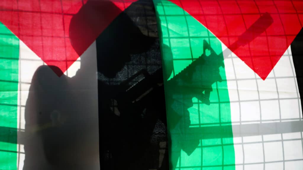 A Palestinian boy holds a toy rifle as he stands behind Palestinian flags during a protest in support of Palestinians. Photo: AP/Mohammed Zaatari.