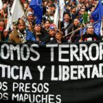 Indigenous Mapuche activist in a street protest holding a banner that reads: "We are not terrorists! Justice and freedom for Mapuche political prisioners." Photo: IWGIA.