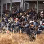Police in riot gear contain migrants attempting to breach the border fence of the Spanish enclave of Melilla. Photo: Javier Bernardo/AP.