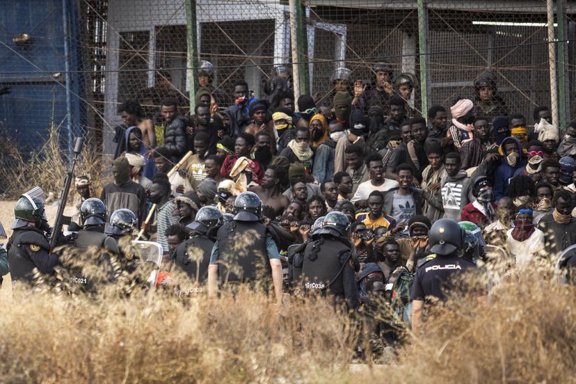 Police in riot gear contain migrants attempting to breach the border fence of the Spanish enclave of Melilla. Photo: Javier Bernardo/AP.