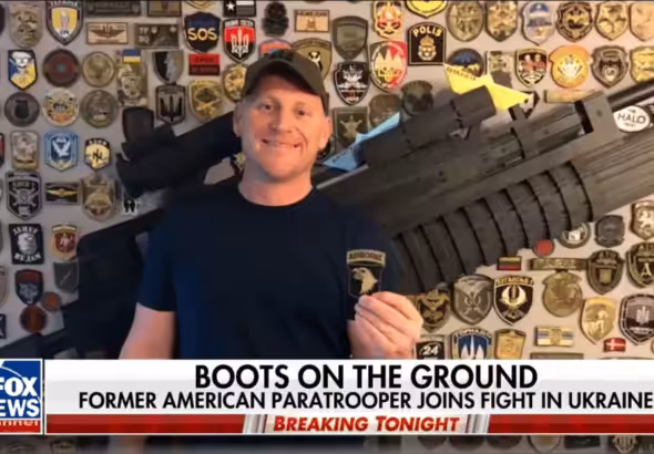 American neo-Nazi Paul Gray on Fox News in front of a wall featuring emblems of fascist militias like the Azov Battallion. Photo: Author