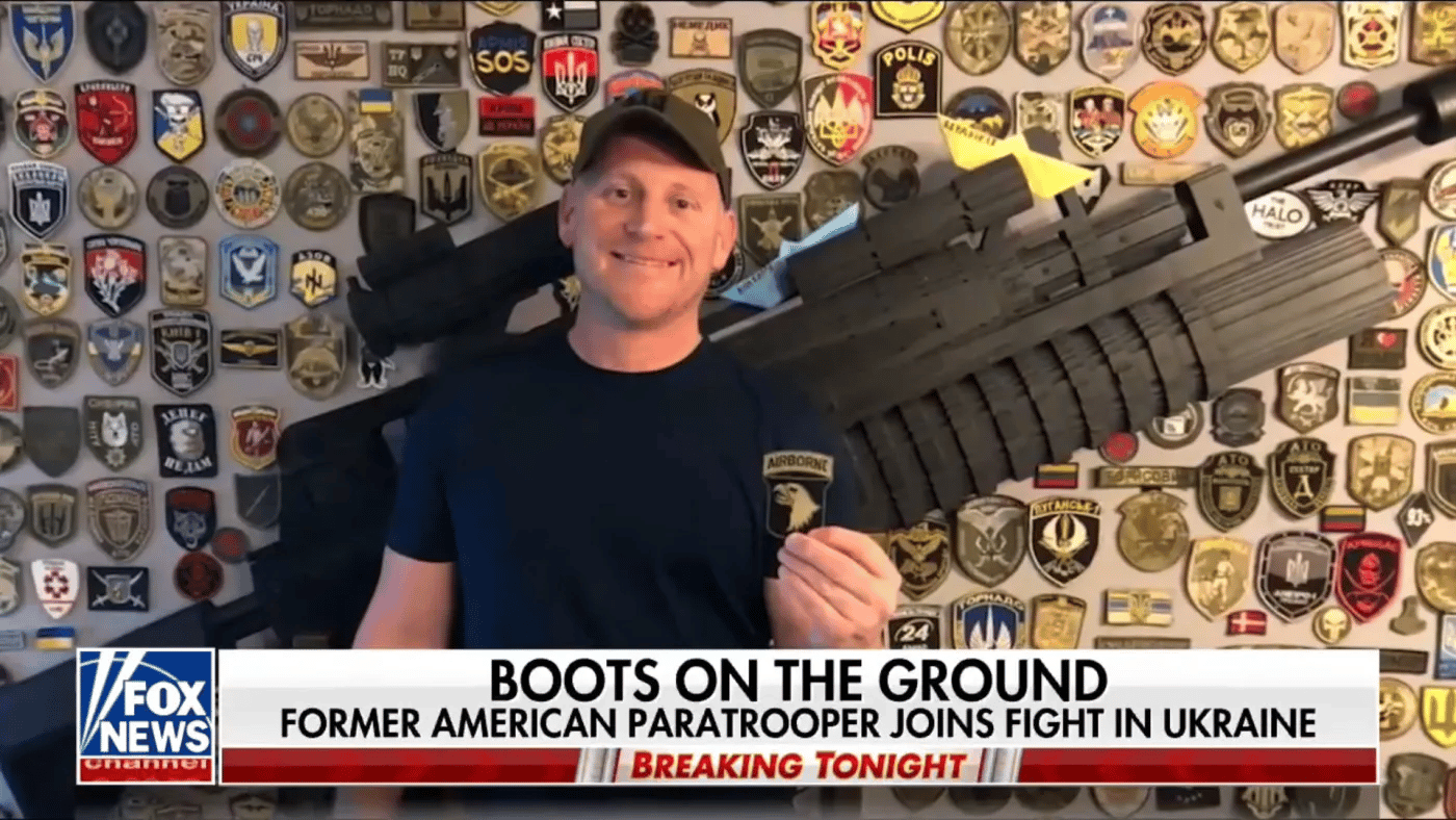 American neo-Nazi Paul Gray on Fox News in front of a wall featuring emblems of fascist militias like the Azov Battallion. Photo: Author