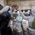 A health worker takes the temperature of European citizens who will take a flight to Madrid, at the Simon Bolivar International Airport in Maiquetia, in La Guaira, Caracas, Venezuela, 26 March 2020. Photo: EPA/Rayner Pena R