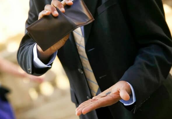 Man showing some coins after squeezing his wallet. Photo: New Eastern Outlook.