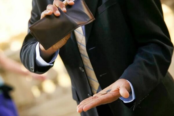 Man showing some coins after squeezing his wallet. Photo: New Eastern Outlook.