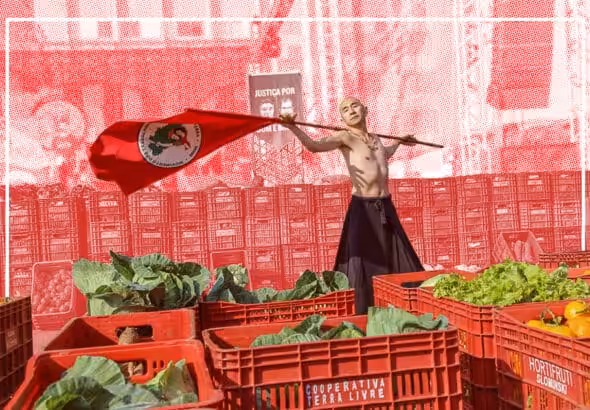 A militant of Brazil's Landless Workers' Movement (MST) flies the organizations flag at a cooperative market. Photo: Wellington Lenon/MST-PR.