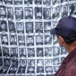 A man looks at a banner carrying photos of some of the hundreds of thousands of people who were killed in the armed conflict in Colombia. File photo.