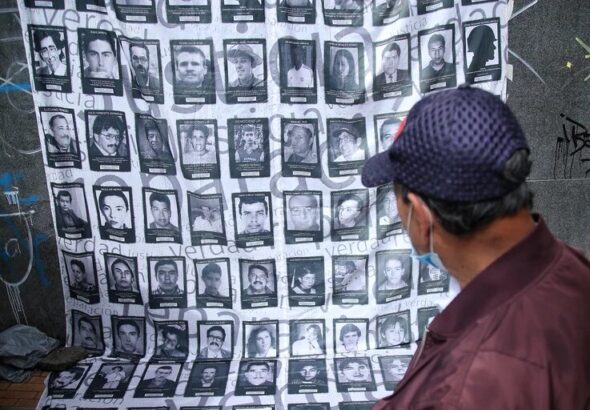 A man looks at a banner carrying photos of some of the hundreds of thousands of people who were killed in the armed conflict in Colombia. File photo.