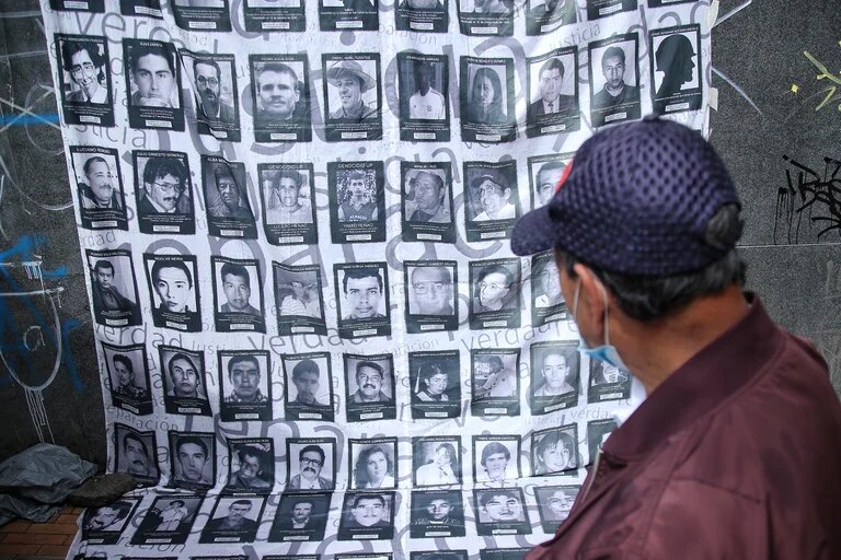 A man looks at a banner carrying photos of some of the hundreds of thousands of people who were killed in the armed conflict in Colombia. File photo.