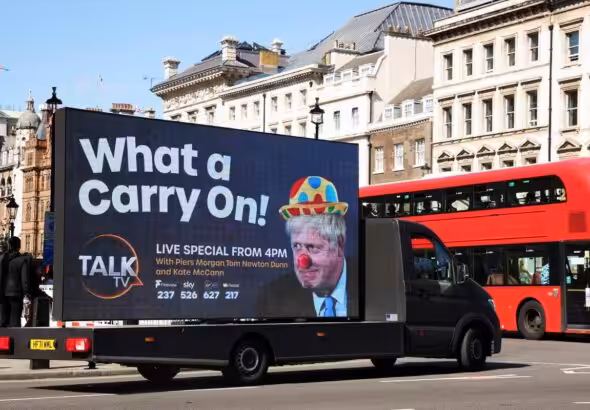 A mobile advertising board, featuring UK Prime Minister Boris Johnson dressed as a clown, drives near Downing Street in London, the United Kingdom. Photo: Phil Noble/Reuters.