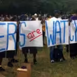 Activists holding a big banner that reads "workers are watching." File photo.