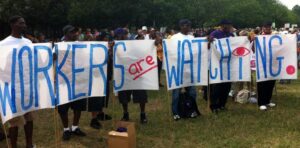 Activists holding a big banner that reads "workers are watching." File photo.