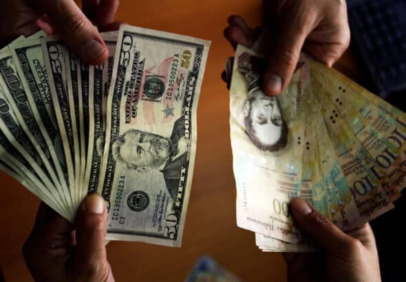 Photo showing bills of 50 and 100 US dollars and 100 Venezuelan bolívars, in Caracas, July 16, 2013. Photo: AFP.