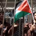 Palestinian prisoners holding a flag behind bars. File photo.