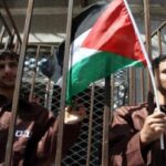 Palestinian prisoners holding a flag behind bars. File photo.