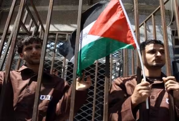 Palestinian prisoners holding a flag behind bars. File photo.