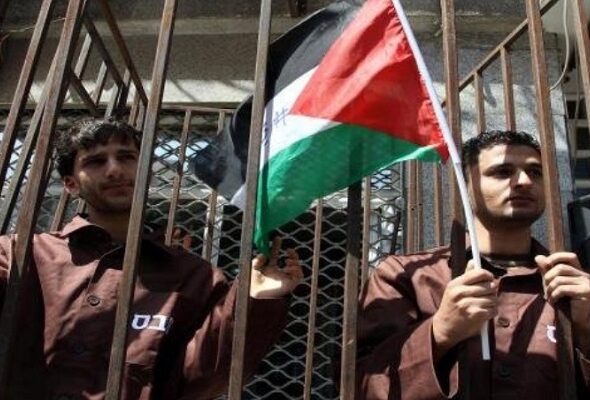 Palestinian prisoners holding a flag behind bars. File photo.