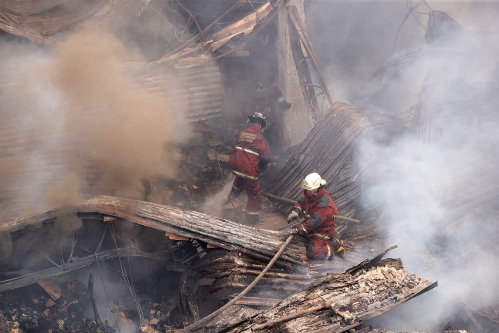 Firefighters work to extinguish the fire at the IVSS warehouse where dialysis machines and medical supplies had been stored. Photo: Rayner Peña R.