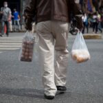 Person crossing the street in Caracas while holding grocery bags. Photo: EFE.