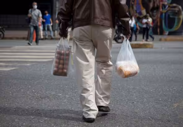 Person crossing the street in Caracas while holding grocery bags. Photo: EFE.