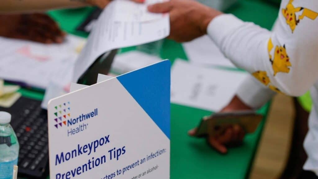 Person showing some papers to an attendant near a sign that reads “Monkeypox Prevention Tips.” Photo: Beijing News/Twitter.