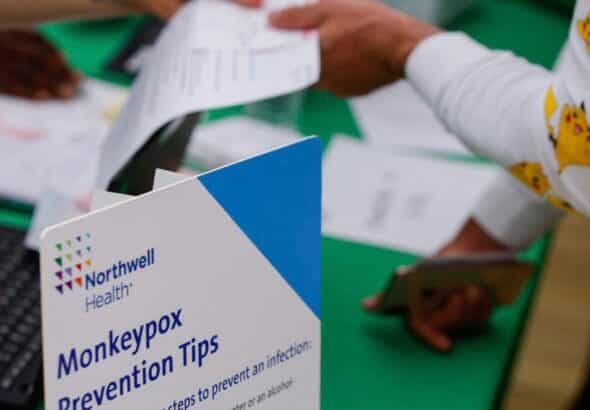 Person showing some papers to an attendant near a sign that reads “Monkeypox Prevention Tips.” Photo: Beijing News/Twitter.