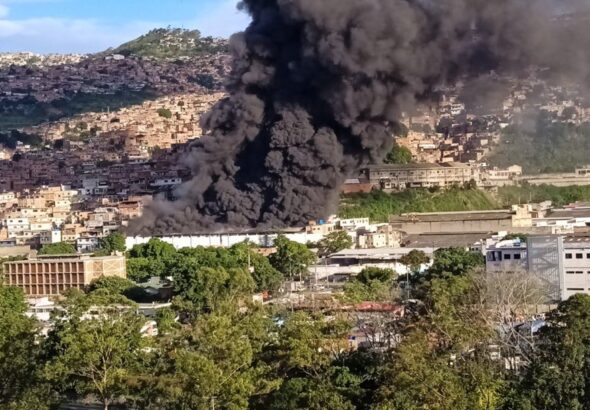 A big trail of black smoke coming out from the IVSS La Yaguara warehouse in Caracas, as seen from a safe distance. Photo: Twitter/@RCR750.