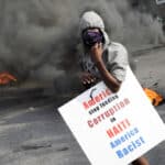 A Haitian protester holds a placard condemning the US domination of Haiti, in capital Port-au-Prince, on October 4, 2019. Photo: Reuters/Andres Martinez Casares  .