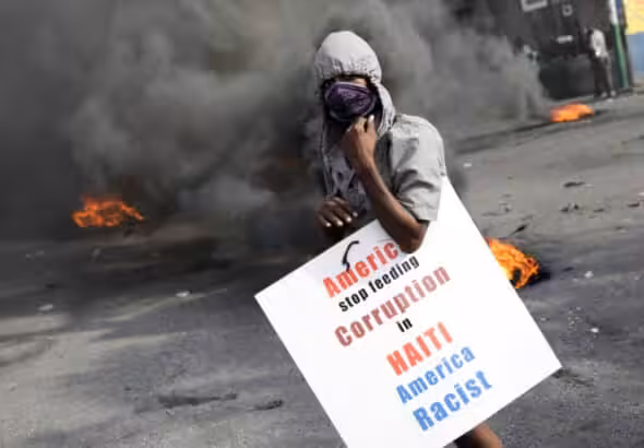 A Haitian protester holds a placard condemning the US domination of Haiti, in capital Port-au-Prince, on October 4, 2019. Photo: Reuters/Andres Martinez Casares  .