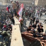 Protesters try to remove concrete barriers and cross the bridge towards the Green Zone area in Baghdad, Iraq. 30 July, 2022. Photo: AP/Ali Abdul Hassan.