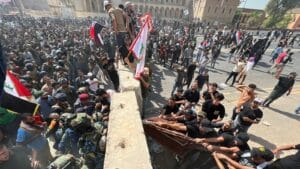 Protesters try to remove concrete barriers and cross the bridge towards the Green Zone area in Baghdad, Iraq. 30 July, 2022. Photo: AP/Ali Abdul Hassan.