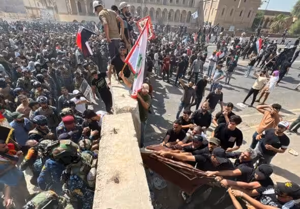 Protesters try to remove concrete barriers and cross the bridge towards the Green Zone area in Baghdad, Iraq. 30 July, 2022. Photo: AP/Ali Abdul Hassan.