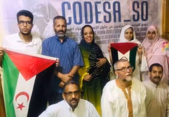 Members of Sahrawi human rights organization CODESA hold the flag of the Sahrawi Arab Democratic Republic as they present their first report on war crimes by Morocco in Western Sahara. Photo: CODESA.