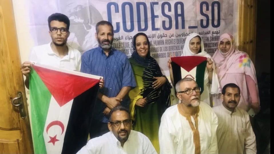 Members of Sahrawi human rights organization CODESA hold the flag of the Sahrawi Arab Democratic Republic as they present their first report on war crimes by Morocco in Western Sahara. Photo: CODESA.