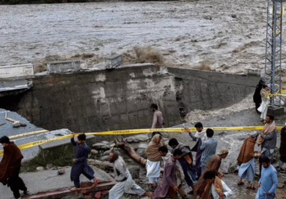 People gather in front of a road damaged by flood waters following heavy monsoon rains in Madian area in Pakistan’s northern Swat Valley on August 27, 2022. Photo: AFP.
