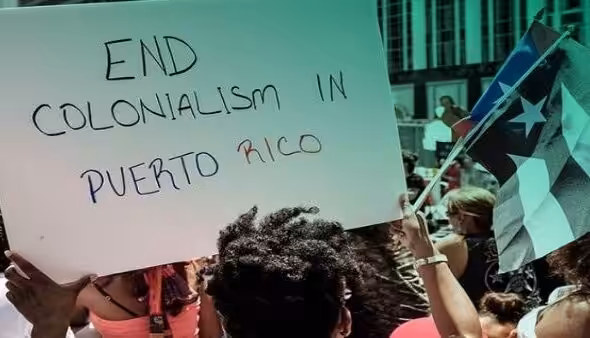 Protesters in Puerto Rico raise a banner demanding an end to US colonization of the island. Photo: Progressive International.