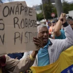 Workers protesting in Caracas against the ONAPRE guidelines. One protester holds a banner that reads "ONAPRE, you robbed us without a gun," on August 11, 2022. Photo: AP/Matias Delacroix.
