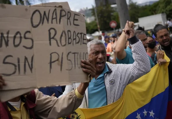 Workers protesting in Caracas against the ONAPRE guidelines. One protester holds a banner that reads "ONAPRE, you robbed us without a gun," on August 11, 2022. Photo: AP/Matias Delacroix.