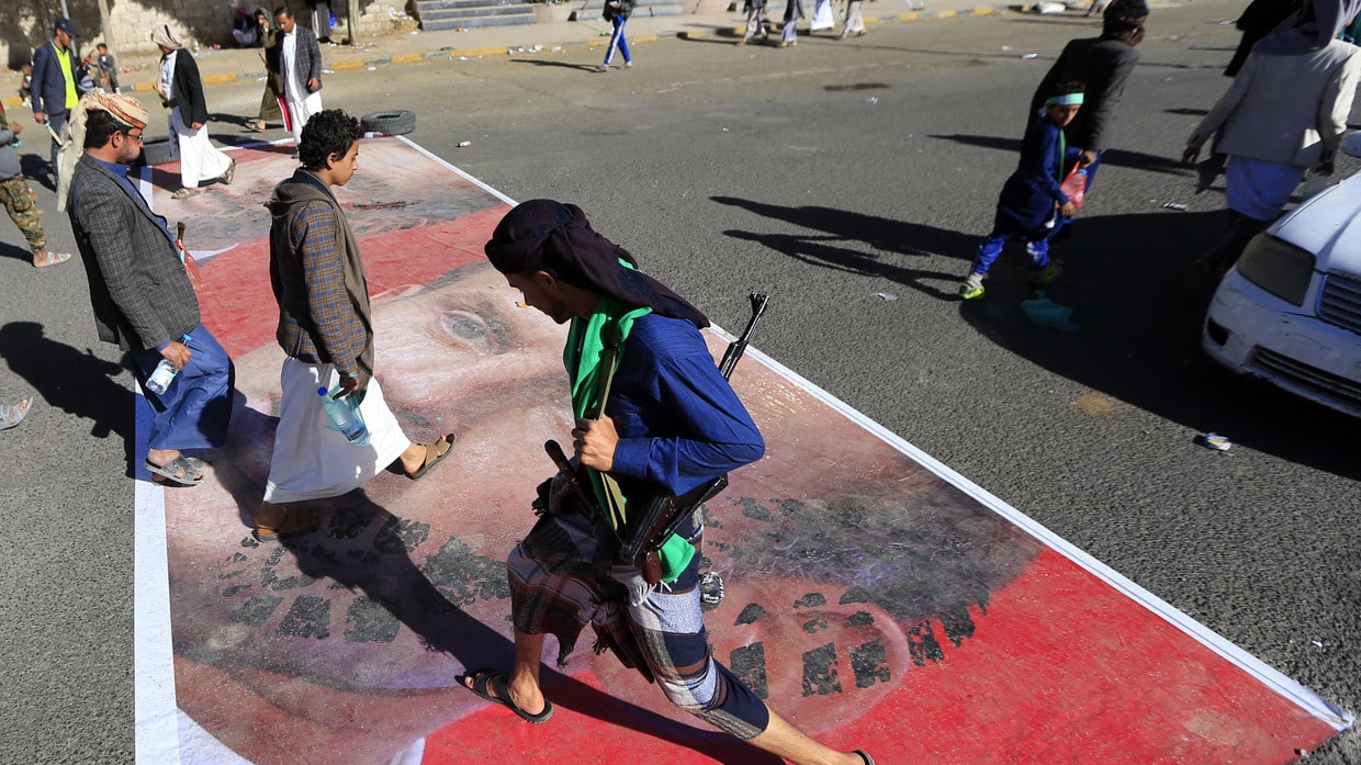 People walking over a street paint with the face of French President Emmanuel Macron. Photo: AFP/Mohammed HUWAIS.