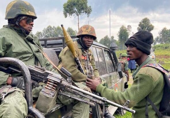 Two heavily armed soldiers in the back of a truck talking with a third one. File photo.