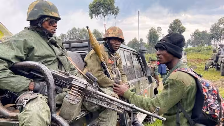 Two heavily armed soldiers in the back of a truck talking with a third one. File photo.