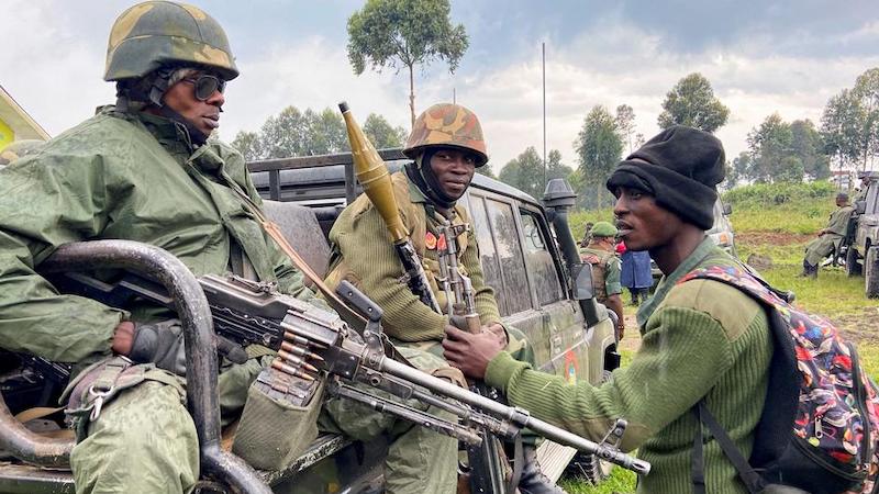 Two heavily armed soldiers in the back of a truck talking with a third one. File photo.