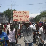 Haitians protesting in the streets, carry a sign that says: "The banks are not innocent in our misery." Photo: Yves Engler.