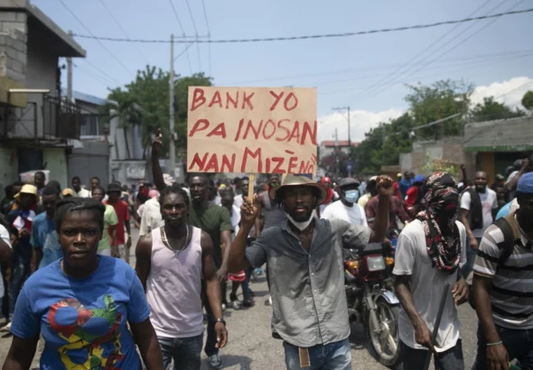 Haitians protesting in the streets, carry a sign that says: "The banks are not innocent in our misery." Photo: Yves Engler.
