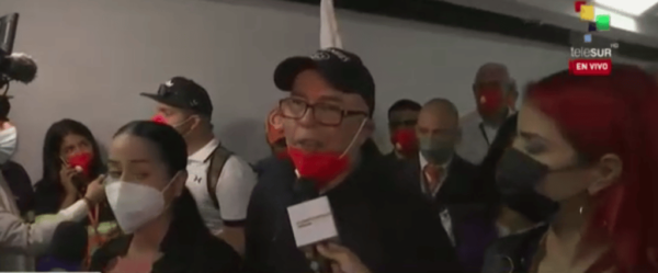 Freed Emtrasur crew members talk to reporters in an airport lobby. The 12 made a stopover in Bolivia before arriving in Venezuela.