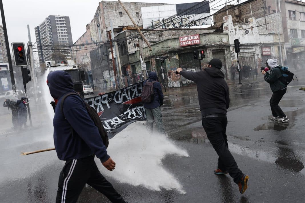 Protesters being attacked with a water cannon during a march on the day that marks the 49th anniversary of the coup against Salvador Allende in Chile. Photo: EFE.