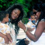 Two Afro-descendant women with babies in their arms looking very happy. File photo.