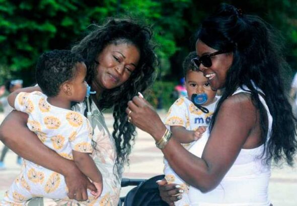Two Afro-descendant women with babies in their arms looking very happy. File photo.